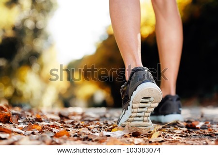 close up of feet of a runner running in autumn leaves training for marathon and fitness healthty lifestyle