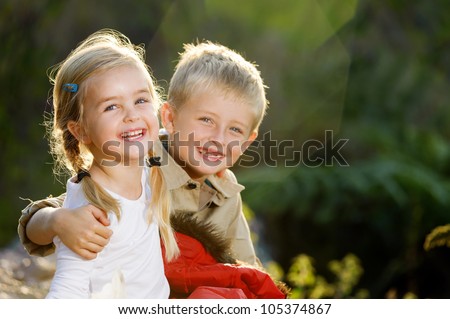 Portrait of adorable brother and sister smile and laugh together while sitting outdoors. happy lifestyle kids