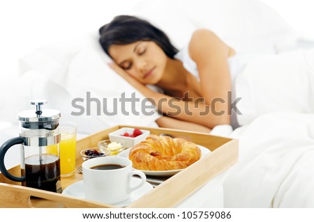 Breakfast in bed for sleeping peaceful latino woman. coffee, yogurt and croissant