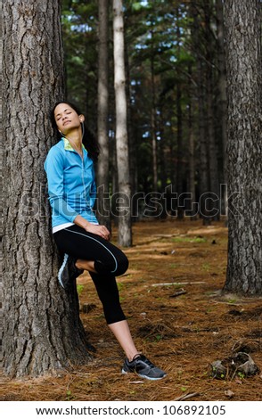 Relaxing runner resting and listening to music on headphones in forest after training. serene scene with copyspace
