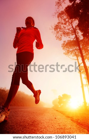 Athlete running on the road in morning sunrise training for marathon and fitness. Healthy active lifestyle latino woman exercising outdoors.