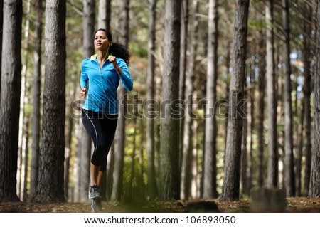 Woman running in wooded forest area, training and exercising for trail run marathon endurance. Fitness healthy lifestyle concept.