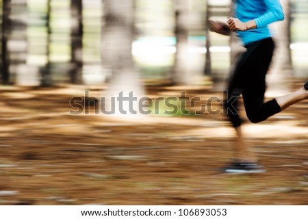 Action motion shot of runner training in forest with blur to show speed and sprinting.