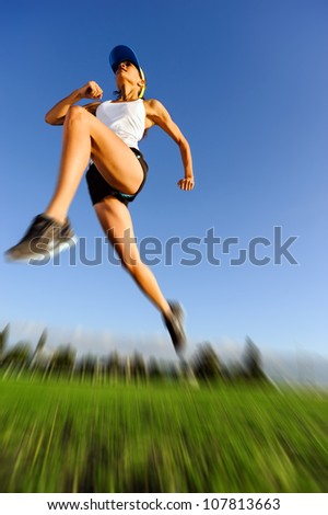 motion blur of athlete jumping outdoors with blue sky and green grass