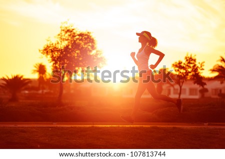 silhouette of a woman athlete running at sunset or sunrise. fitness training of marathon runner.