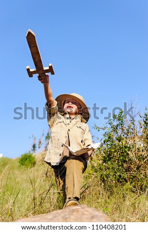 young child playing pretend adventure explorer with wooden sword and treasure map.