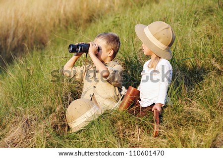 cute children playing pretend safari game together outdoors. happy brother and sister