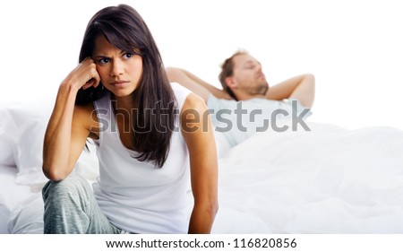 Couple fighting in bed, woman upset, thinking and man sleeping in background. unhappy relationship