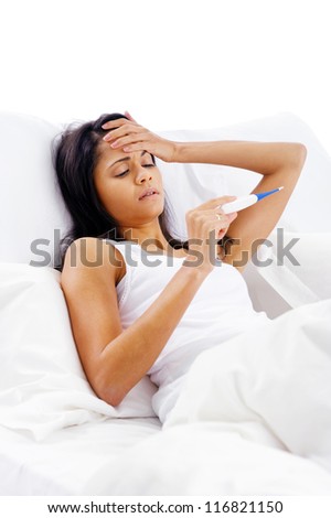 ill woman taking her temperature in bed wile feeling sick and with fever