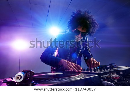 nightclub dj playing music on deck with vinyl record headphones light flare clubbing party scene