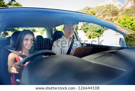 Learner driver student driving car with instructor. happy and confident smiling girl