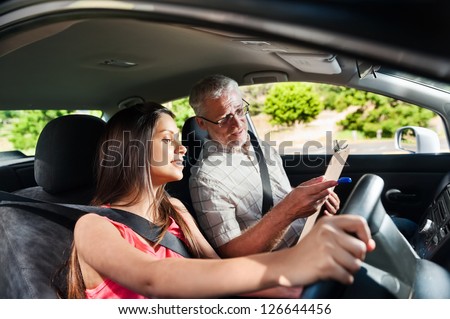 Learner driver student driving car with instructor. happy and confident smiling girl