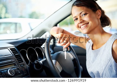 Happy woman new car owner smiling and showing keys in driver seat