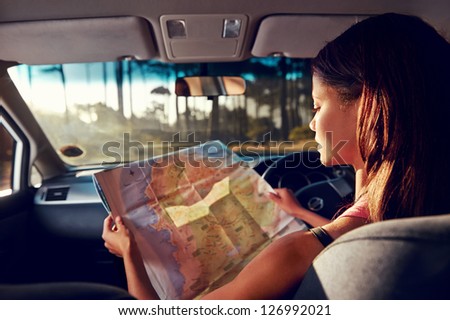 Woman on vacation looking at map for directions while driving in car