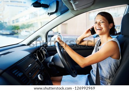 attractive businesswoman smiling while talking on the phone and driving to work, happy carefree business