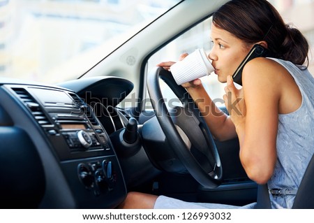 Businesswoman multitasking while driving, drinking coffee and talking on the phone
