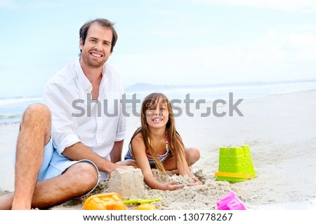 happy healthy family father and daughter building sand castle on the beach smiling and carefree