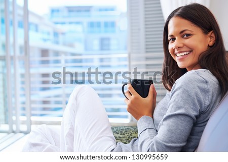 Woman enjoys fresh coffee relaxing at home on the sofa couch