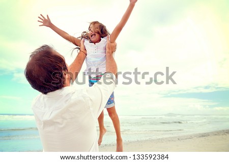 Healthy father and daughter playing together at the beach carefree happy fun smiling lifestyle Healthy father and daughter playing together at the beach carefree happy fun smiling lifestyle