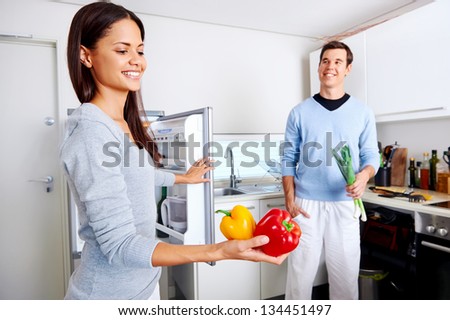 healthy eating couple get fresh vegetables out of the fridge to cook food