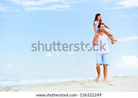 loving father with daughter on shoulders walking on the beach carefree and happy