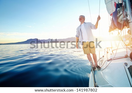 Sunrise Sailing Man On Boat In Ocean With Flare And Sunlight On Calm Morning On The Water