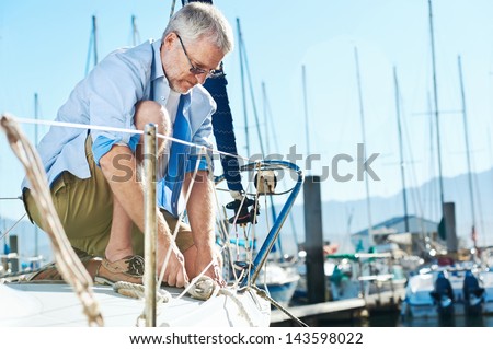 portrait of senior man tying knot and securing a mooring for his hobby yacht sail boat