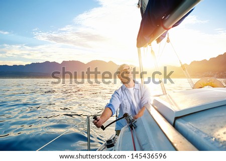 sunrise sailing man on boat in ocean with flare and sunlight on calm morning on the water