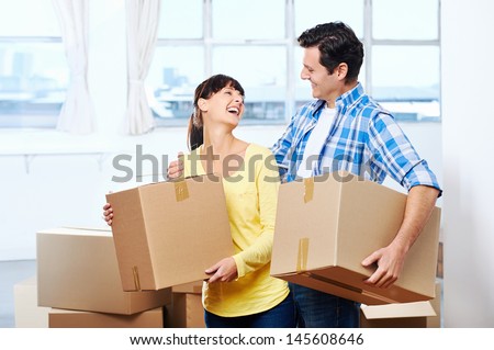 Happy couple carrying boxes moving into new home apartment house