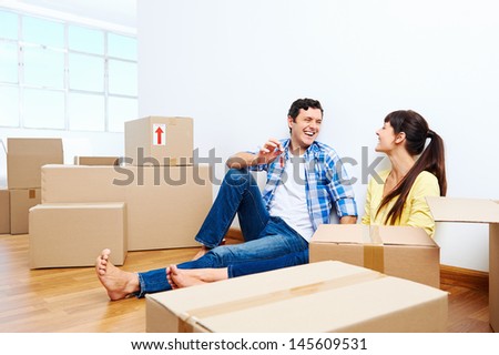couple celebrating new home handing keys and moving boxes