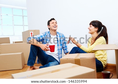 couple celebrating new home handing keys and moving boxes