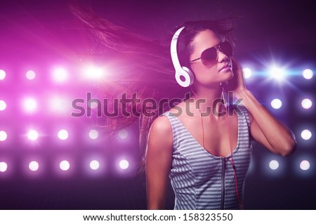 Portrait of woman dj enjoying music on headphones and nightclub lights
