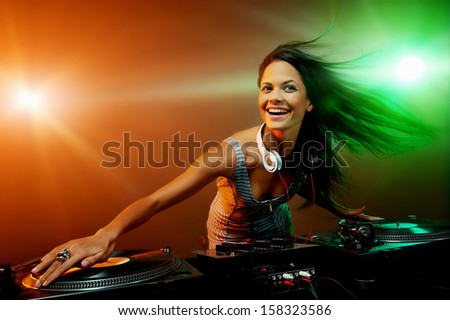 Cute dj woman having fun playing music on vinyl record deck at club party nightlife lifestyle