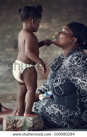 Loving mother kissing her baby girl rural african real people