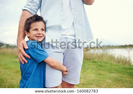 Happy young boy hugging his dad and smiling in the park