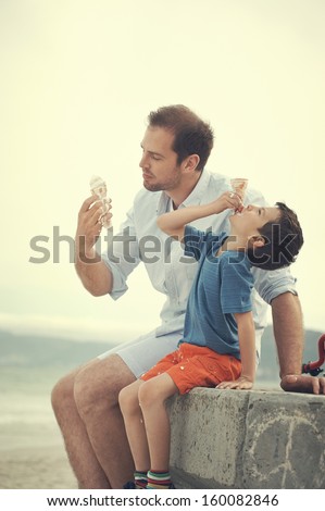 Father And Son Eating Icecream Together At The Beach On Vacation Having Fun With Melting Mess