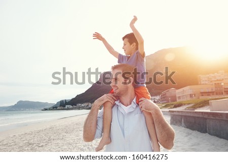 Son On Fathers Shoulders At The Beach Having Fun At Sunset Together