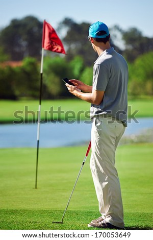 modern golf man with smart phone taking score on mobile gps device next to green