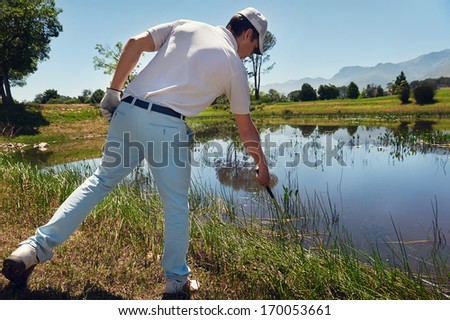 lost golf ball in water hazard golfer looking in reeds