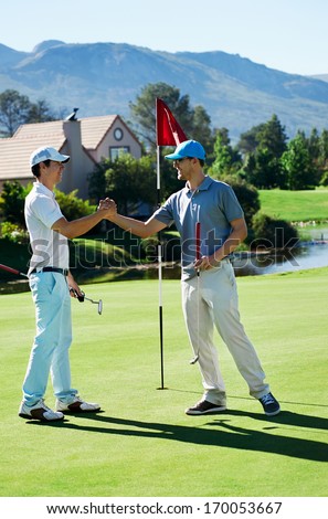 golf friends shake hands after a game on the course smiling and happy