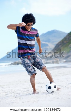 Hispanic Brasil man playing soccer on beach with dribble skill and ball on vacation