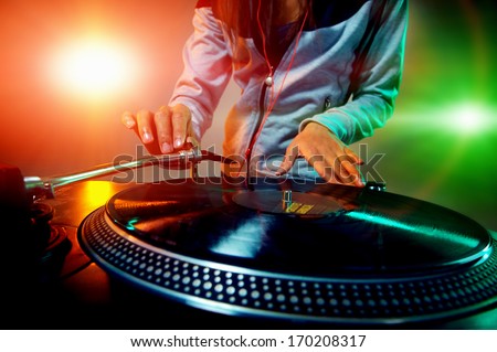 Dj hands on equipment deck and mixer with vinyl record at party