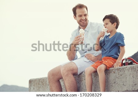 Father and son eating ice cream together at the beach on vacation having fun with melting mess