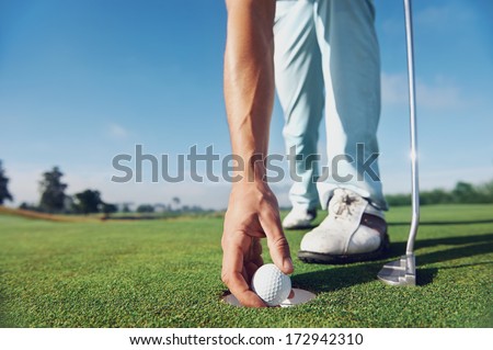 Golf man putting on green for birdie while on vacation