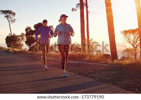 Running at sunrise couple exercising for marathon and workout fitness