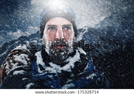 adventure mountain man in snow blizzard looking on with determination and courage