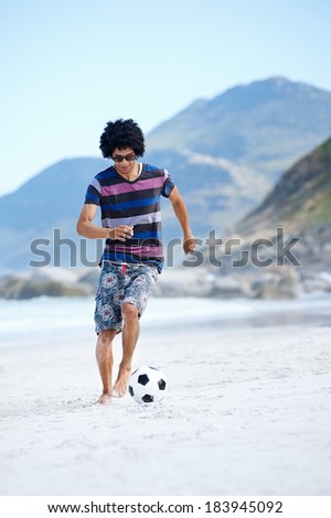 Hispanic Brasil man playing soccer on beach with dribble skill and ball on vacation