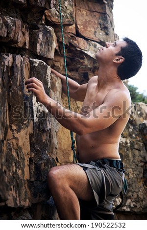 An attractive man with no shirt on rock climbing