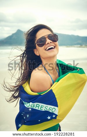 Latino woman with Brasil flag laughing and smiling in support of Brazilian soccer fan