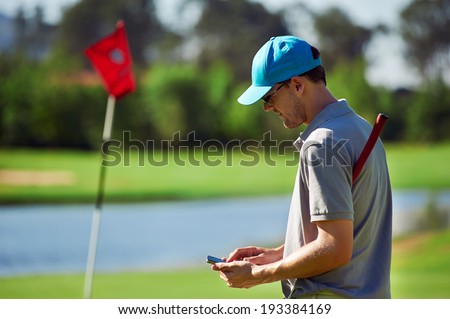 modern golf man with smart phone taking score on mobile gps device next to green